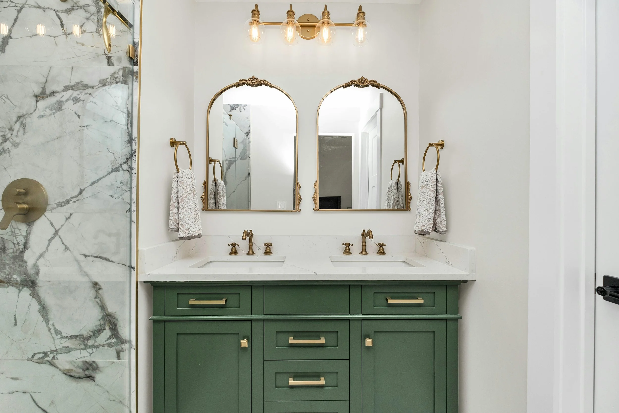 Luxury bathroom with dual sink and green cabinetry
