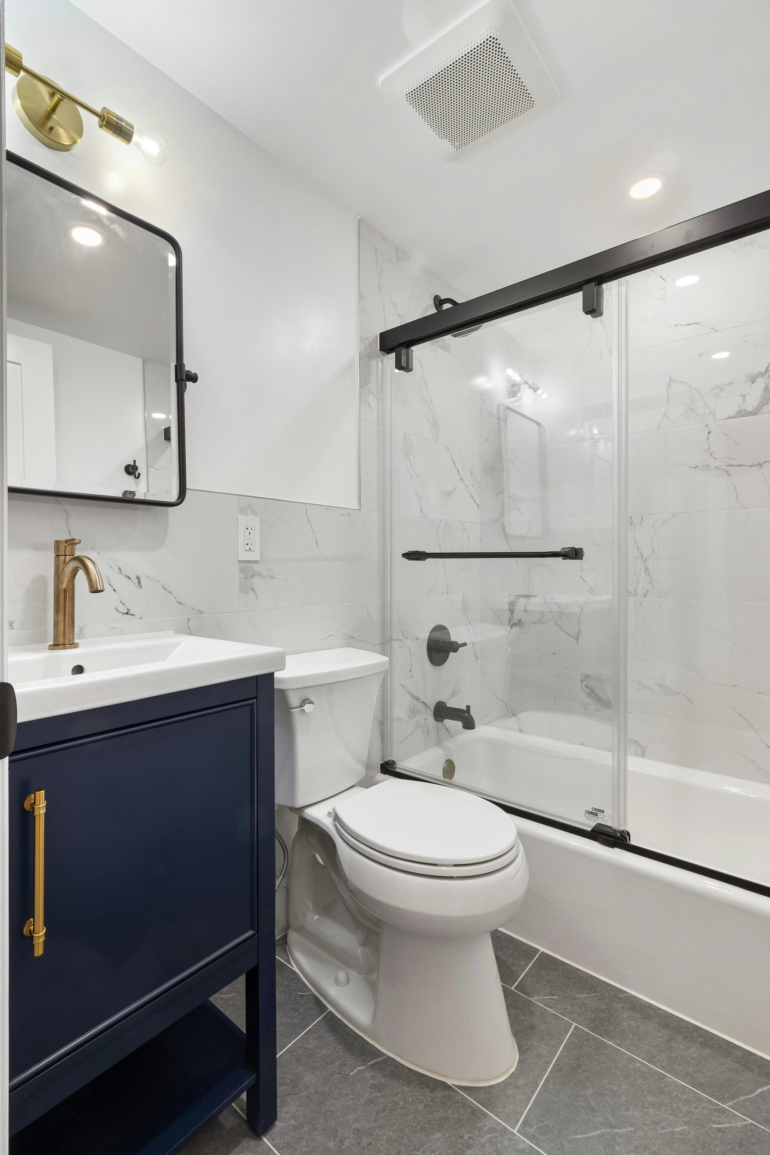 Modern bathroom with navy blue vanity and marble tile